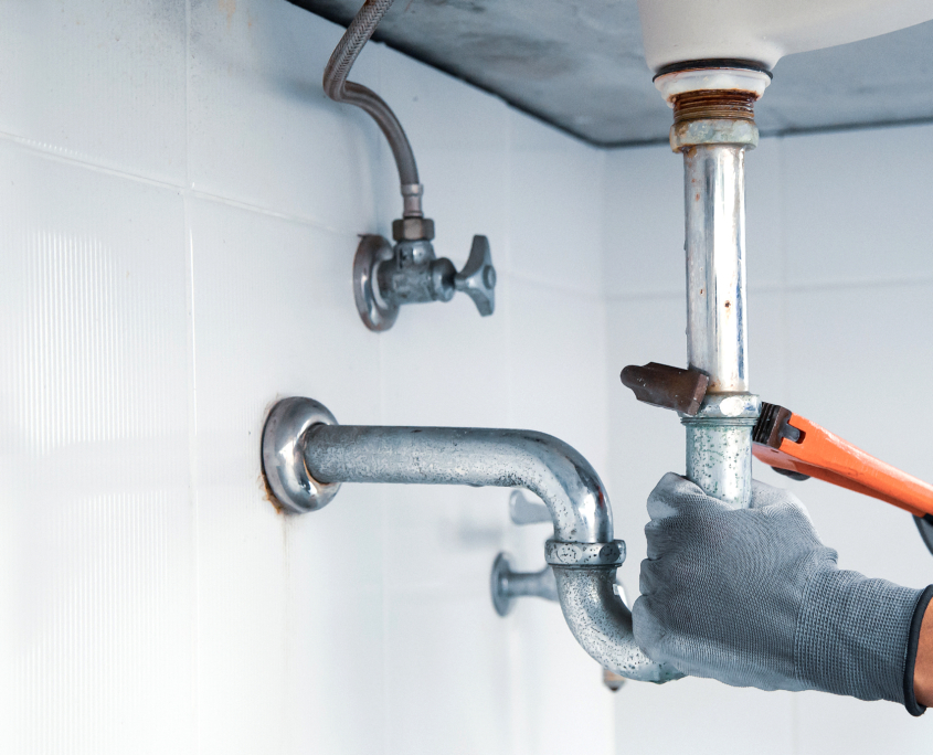 plumber using wrench to repair water pipe